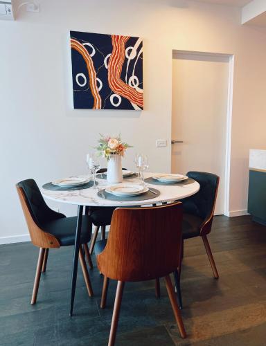 a dining room table with chairs and a painting on the wall at Melbourne CBD 2B2B1S with City & Sea Views in Melbourne
