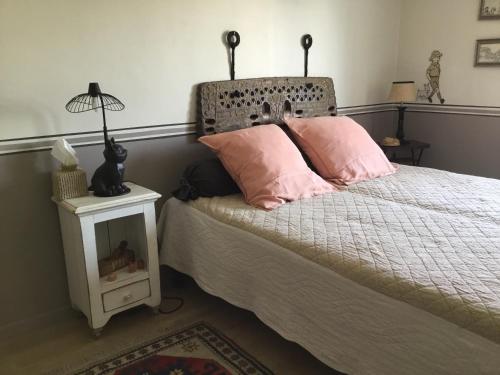 ein Schlafzimmer mit einem Bett mit rosa Kissen darauf in der Unterkunft BnB Montacutain in Montaigu-Vendée
