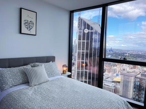 a bedroom with a bed and a large window at Melbourne CBD 2B2B1S with City & Sea Views in Melbourne