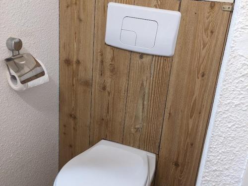 La salle de bains est pourvue de toilettes blanches et d'un mur en bois. dans l'établissement Studio cosy aux pieds des pistes avec balcon et coin montagne - La Joue du Loup - FR-1-504-621, à Saint-Étienne-en-Dévoluy
