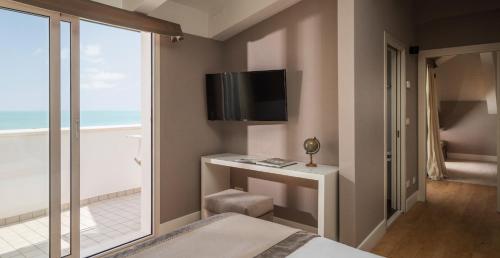 a bedroom with a bed and a tv and a window at Hotel Maestrale in Riccione
