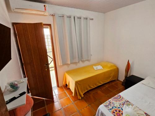 a room with a bed and a door with a window at Pousada Flor de Lótus Suites Carneiros in Tamandaré