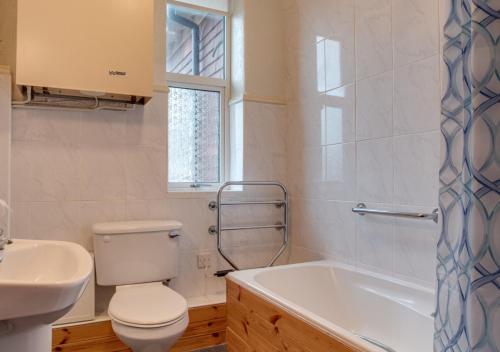 a bathroom with a toilet and a sink and a tub at Seaspray in Seaton