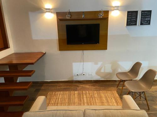 uma sala de estar com uma televisão e um sofá e cadeiras em Casa com ótima localização em São Sebastião