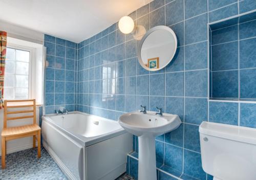 a blue tiled bathroom with a sink and a tub at The Malt House in Colyton