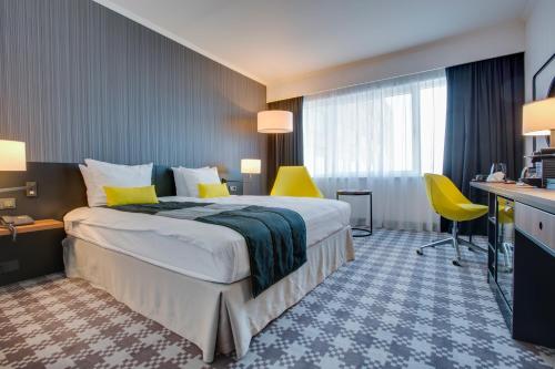 ein Hotelzimmer mit einem großen Bett und gelben Stühlen in der Unterkunft Radisson Blu Hotel Amsterdam Airport, Schiphol in Schiphol