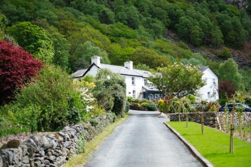 una calle en un pueblo con casas y un muro de piedra en Ty Afon - River House, en Beddgelert