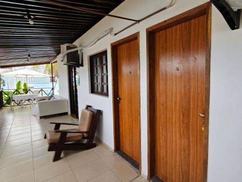 a room with a wooden door and a chair at Pousada Flor de Lótus Suites Carneiros in Tamandaré
