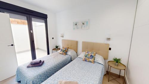 two beds in a room with a window at Villa Morera - A Murcia Holiday Rentals Property in Los Alcázares