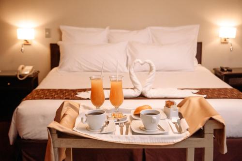 a tray with two glasses of orange juice on a bed at Hotel Carrera in Lima