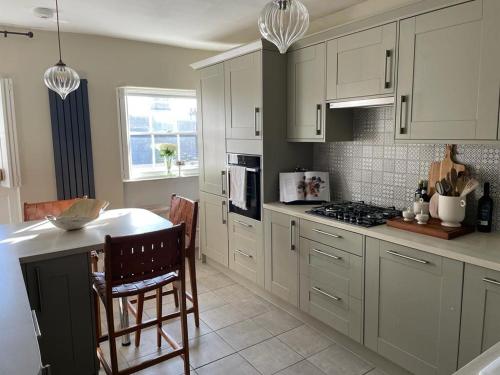 La cuisine est équipée de placards blancs et d'un four avec plaques de cuisson. dans l'établissement Luxury apartment, 60 High St, St Martins, à Lincolnshire
