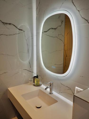 La salle de bains est pourvue d'un lavabo et d'un miroir rond. dans l'établissement Villa de prestige vue sur Baie de Canche, à Le Touquet-Paris-Plage