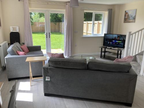sala de estar con sofá y TV en Newly built 3 Bed house with ample parking 1 en Balderton