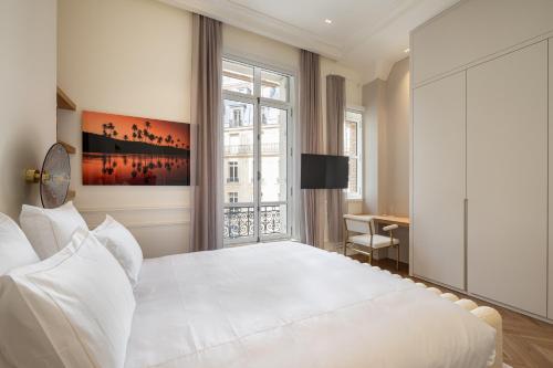 une chambre avec un grand lit blanc et un bureau dans l'établissement Appartement Avenue Montaigne - Paris Champs Elysées, à Paris