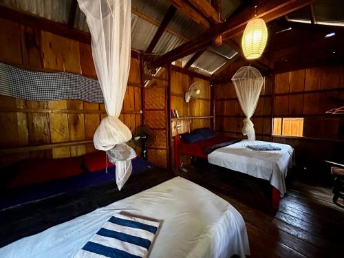 a room with two beds in a wooden cabin at Easy Tiger Garden Bungalows - by Beach House Cambodia in Koh Rong Sanloem