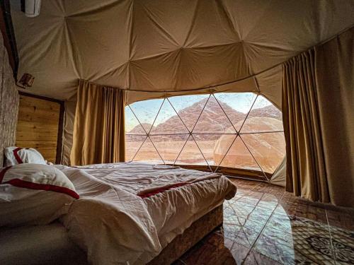 Sky Light Wadi Rum في وادي رم: غرفة نوم مع نافذة كبيرة في خيمة