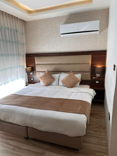 a bedroom with a large bed with a ceiling at AlQimah Hotel Apartments in Amman