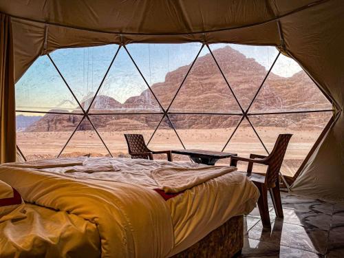 a bed in a tent with a view of the desert at Sky Light Wadi Rum in Wadi Rum