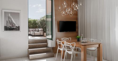 comedor con mesa, sillas y TV en Metropol Ceccarini Suite - Luxury apartments, en Riccione