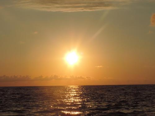 an image of the sun setting over the ocean at OK house! in K'obulet'i