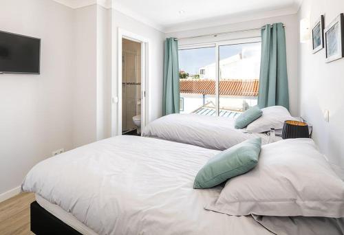 two beds in a room with a window at Villa Benagil with stunning views and roof terrace with private heated pool in Lagoa