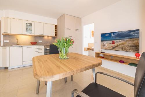 a kitchen with a wooden table with a vase of flowers on it at Dünenrose in Baabe