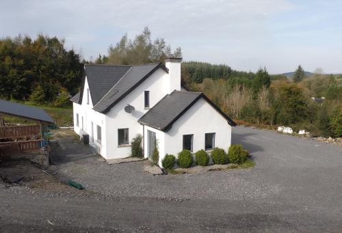 uma casa branca com um telhado preto em Cornacarta Holiday House em Boyle