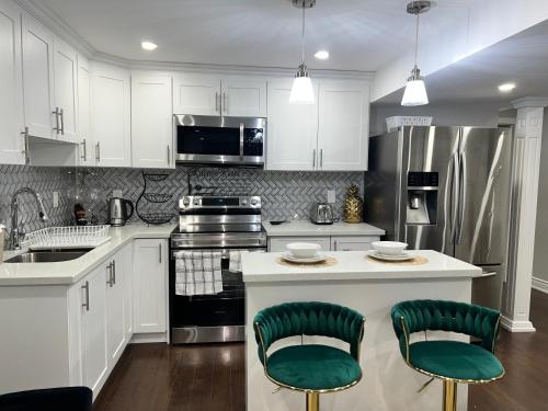 a kitchen with white cabinets and green bar stools at Tosam Luxury Lodge Two Bedroom Suite in Brampton