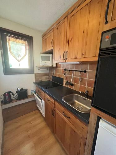 une petite cuisine avec un évier et un micro-ondes dans l'établissement Studio avec magnifique vue montagne - Praloup 1500, à Uvernet