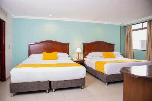 a bedroom with two beds with orange and yellow pillows at Hotel Faranda Express Puerta Del Sol Barranquilla, A Member of Radisson Individuals in Barranquilla
