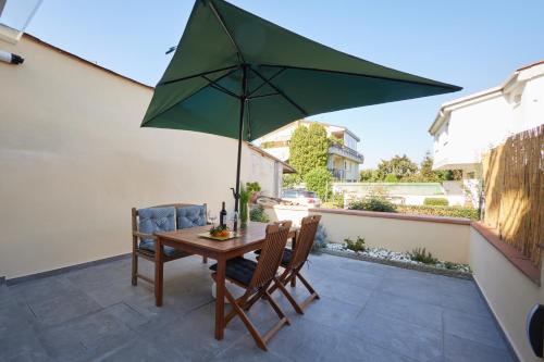 einen Tisch und Stühle mit einem grünen Sonnenschirm auf einer Terrasse in der Unterkunft Torregalli- Terrace Apartment in Florenz