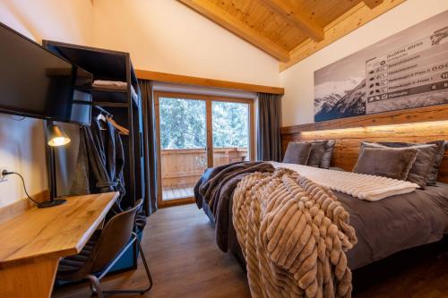 a bedroom with a bed and a desk and a television at Chalet Zillertal Arena in Krimml