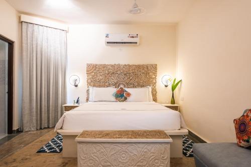 a bedroom with a large white bed and a couch at Sashas Holiday Village in Vagator