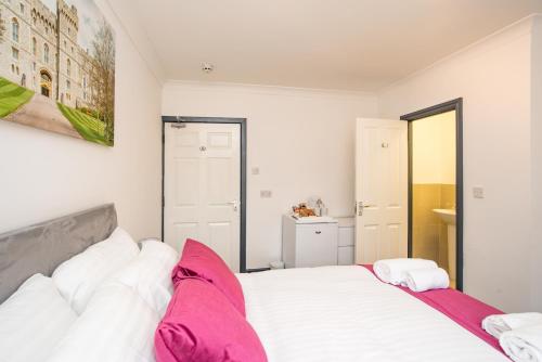 a bedroom with a large white bed with pink pillows at Wilson Lodge in Maidenhead
