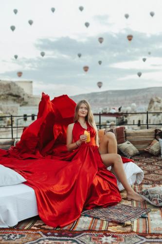 a woman in a red dress sitting on a bed at Angel View Suites in Goreme
