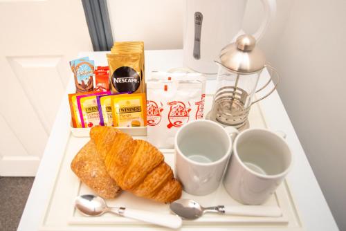 a tray with croissants and cups on a table at Wilson Lodge in Maidenhead