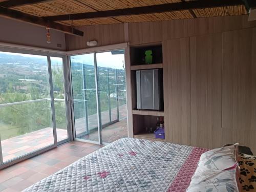 um quarto com uma cama e uma grande janela em Amonitas Glamping Deluxe em Tinjacá