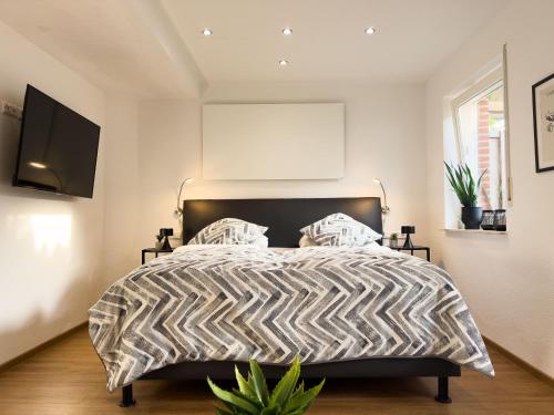 Schlafzimmer mit einem Bett mit einer schwarzen und weißen Bettdecke in der Unterkunft Zentrales Apartment für 2 *Bogenstraße* in Norderney