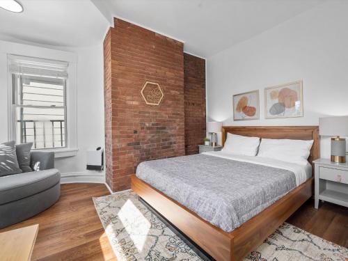 a bedroom with a bed and a brick wall at Shadyside, Pittsburgh, Modern and Bright 1 Bedroom Unit4 with Free Parking in Pittsburgh