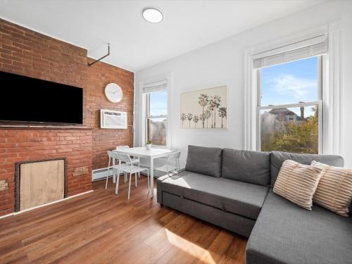 a living room with a couch and a brick wall at Shadyside, Pittsburgh, Modern and Bright 1 Bedroom Unit4 with Free Parking in Pittsburgh