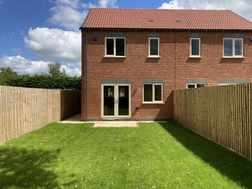a brick house with a fence and a yard at Newly built 3 Bed House with Ample Parking 2 in Balderton