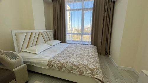 Ce lit se trouve dans un dortoir doté d'une grande fenêtre. dans l'établissement Апартамент КРИСТАЛЛ, à Bishkek