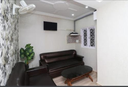 a living room with a leather couch and a tv at Nilansh homes and hotels in Lucknow