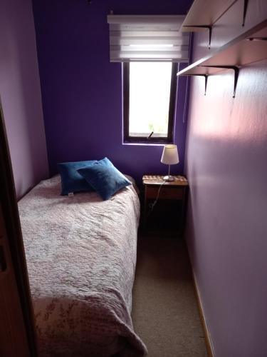 Dormitorio púrpura con cama y ventana en Jeca Centro, en Valdivia