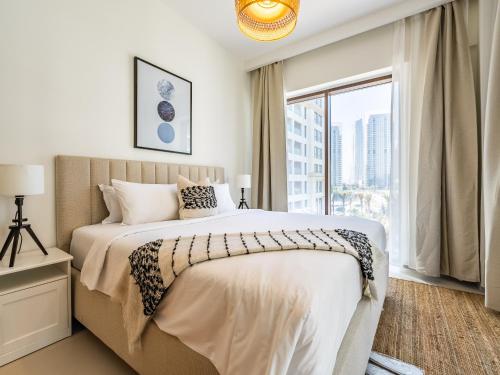 a bedroom with a large bed and a large window at Dubai Creek Gem, Stylish Condo With Two Balconies in Dubai