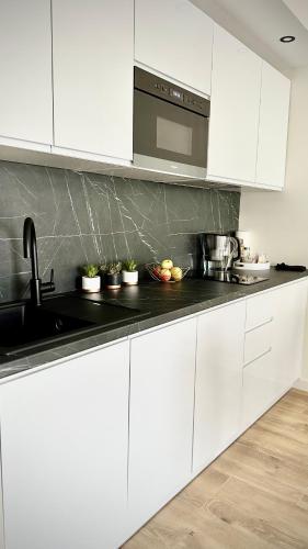 a kitchen with white cabinets and a black counter top at Apartament Elegant 2 in Przemyśl