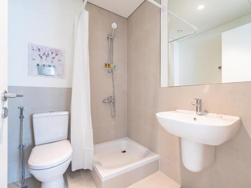 a white bathroom with a toilet and a sink at Dubai Creek Gem, Stylish Condo With Two Balconies in Dubai