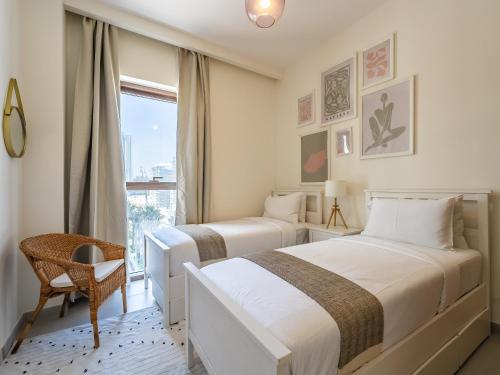 two beds in a room with a window at Dubai Creek Gem, Stylish Condo With Two Balconies in Dubai
