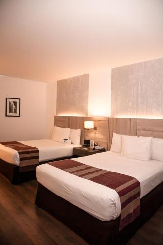 a hotel room with two beds and a lamp at Aku Hotels in Lima