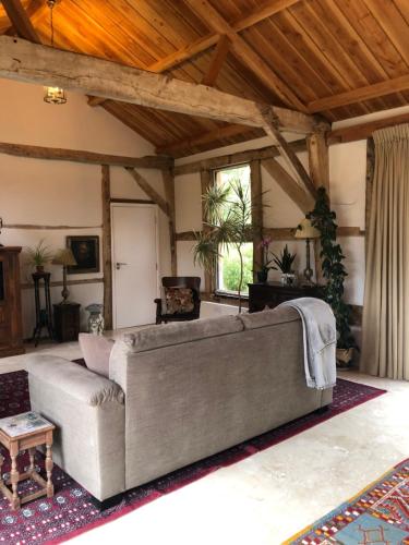 a large couch in a living room with a wooden ceiling at The Barn in Romsey